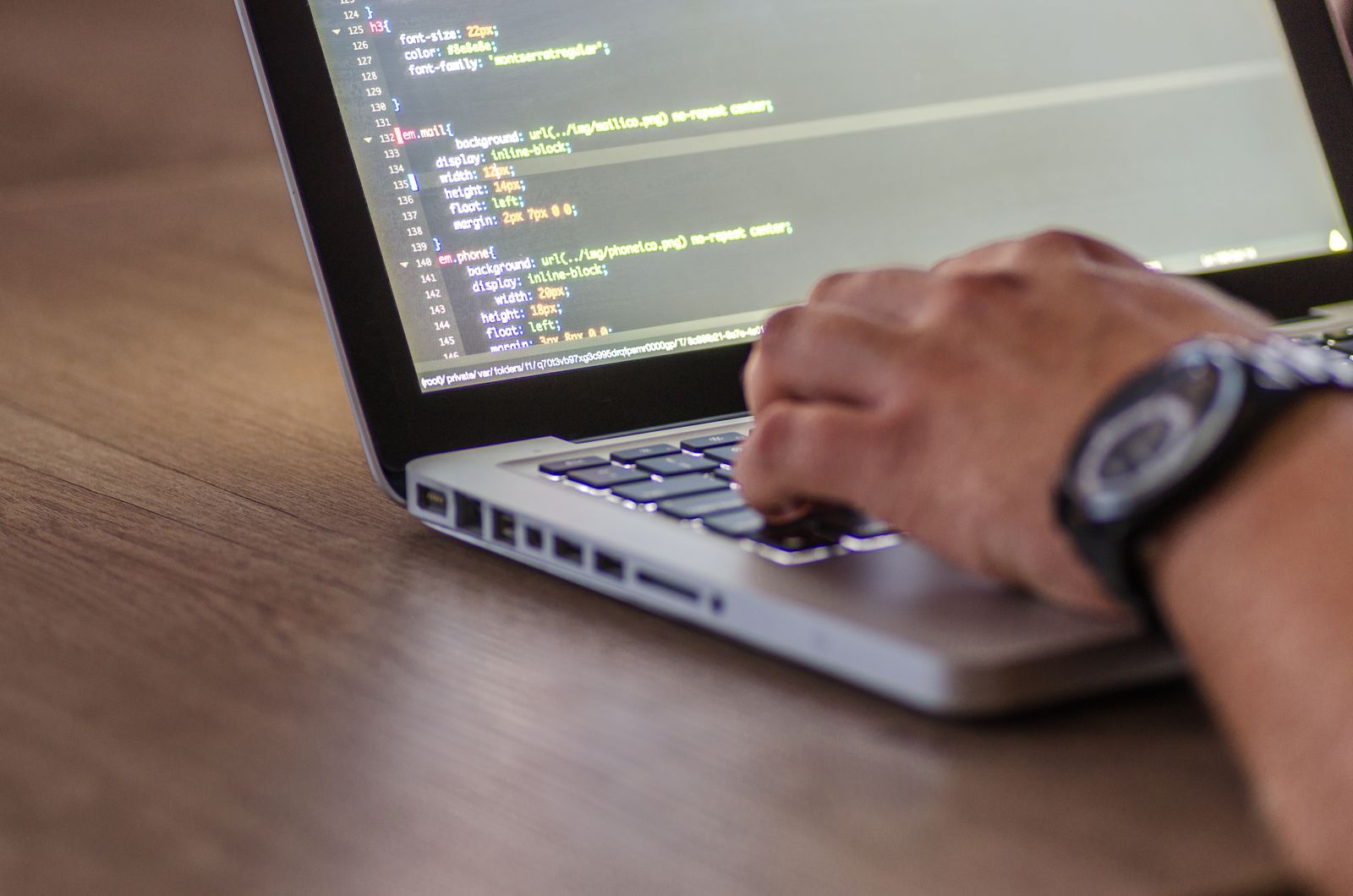 Laptop on a desk with hands on the keyboard during software work